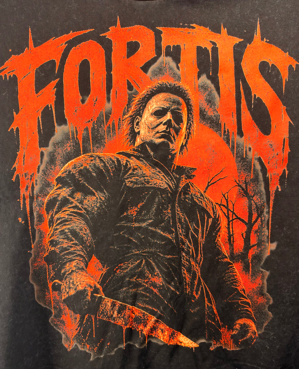 Close-up of the orange Halloween character graphic and Fortis lettering on the acid-wash T.